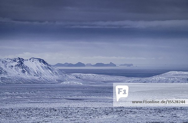 Keldnahraun lava covered with snow Westman Islands in the background Iceland.
