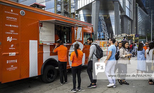 Passer-by line up for free smoothies at the IHG Hotels and Resorts branding event outside of Hudson Yards in New York on Thursday June 6 2019. Smoothies tacos and a chance to win a two night stay in their Crown Plaza HY36 adjacent to Hudson Yards was offered. (© Richard B. Levine).