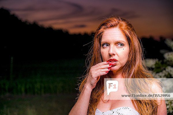40 year old redheaded woman in a white dress in a garden setting in the spring.