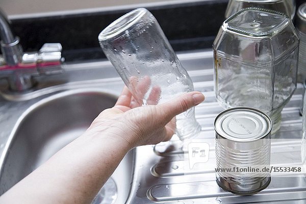 Woman washing out jars and tins for recycling