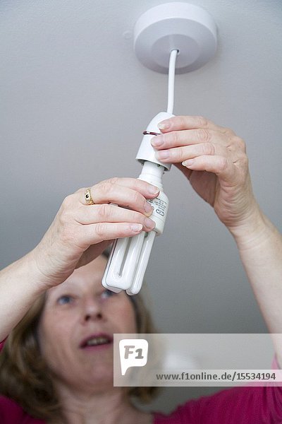Woman changing an energy saving lightbulb