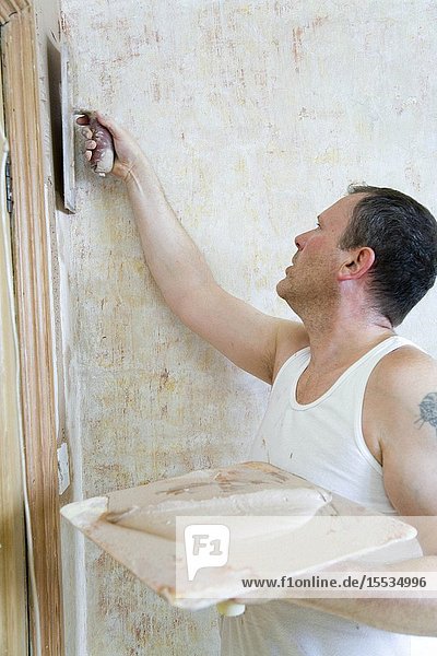 Man using a hawk and trowel to plaster a wall