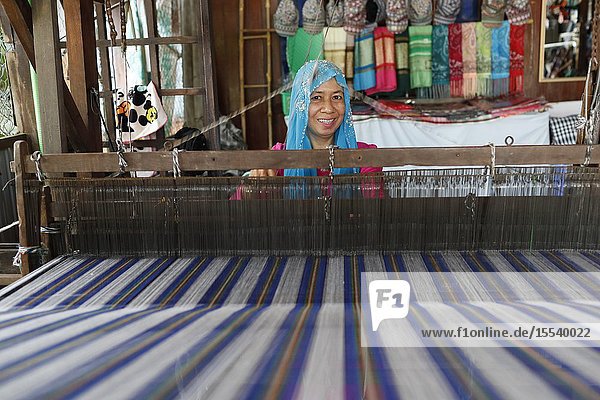Traditional hand loom. Local muslim woman diligently weaving colourful scarves. Chau Doc. Vietnam.