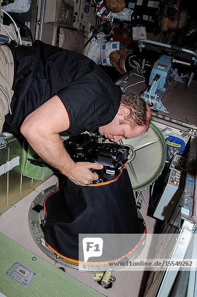 At a window in the International Space Station's Zvezda Service Module Russian cosmonaut Oleg Kotov Expedition 38 commander uses a digital camera photospectral system during a session for the Seiner ocean photography experiment.