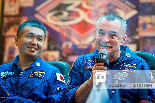 Expedition 38 Soyuz Commander Mikhail Tyurin of Roscosmos right talks as Flight Engineer Koichi Wakata of the Japan Aerospace Exploration Agency listens from quarantine behind glass during the final press conference held a day ahead of their launch with fellow crew mate Flight Engineer Rick Mastracchio of NASA to the International Space Station Nov. 6 2013 at the Cosmonaut Hotel in Baikonur Kazakhstan.