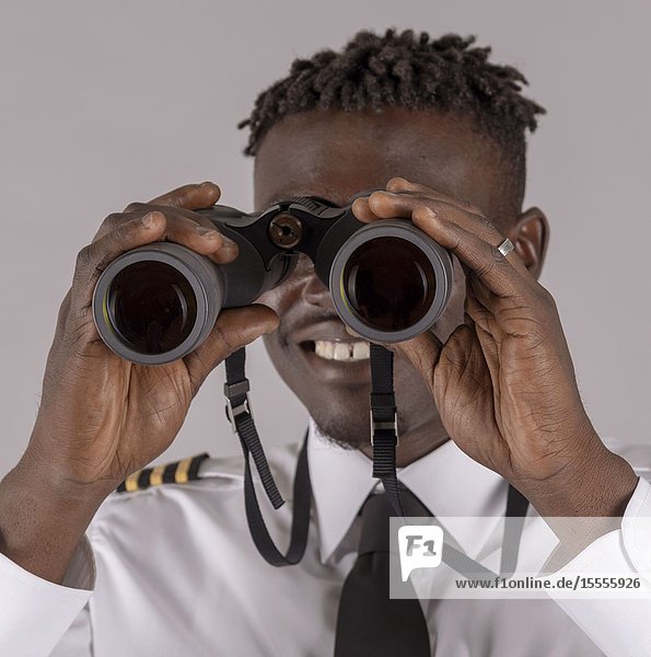 London UK April 2019. Young airline pilot using a pair of binoculars with focus on hands and lenses.