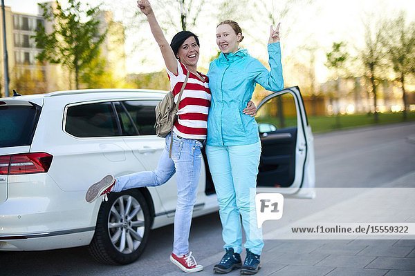 Two adventurous women in front of car with open door ready to start adventure in Munich Germany