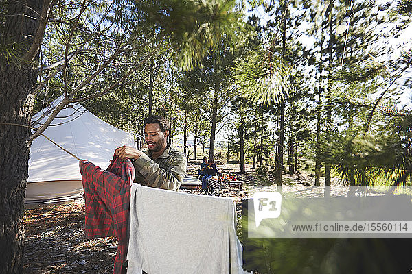 Man hanging laundry on clothesline at campsite in woods