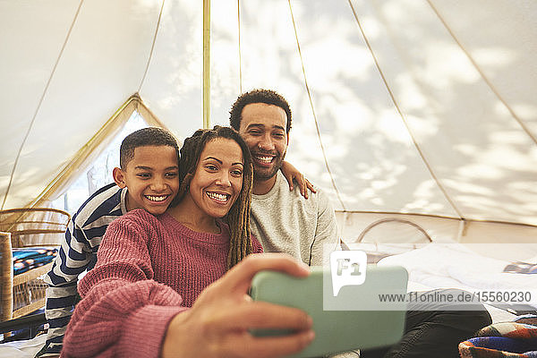 Happy  affectionate family taking selfie in camping yurt