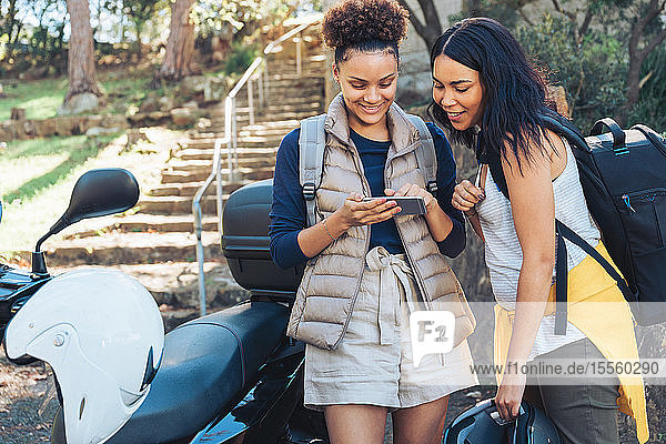 Junge Frauen Freunde mit Smartphone auf Motorroller