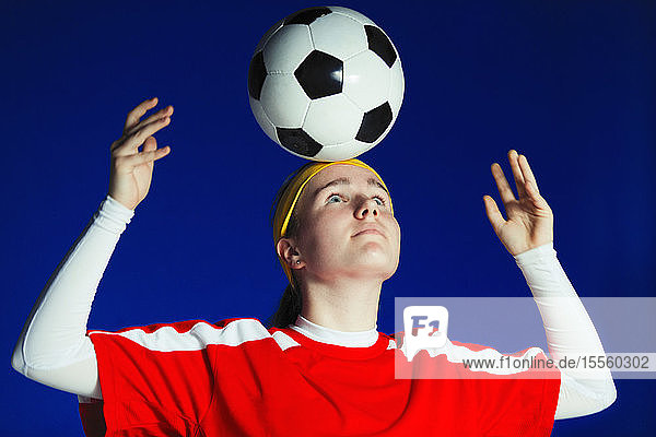 Teenager-Fußballspielerin balanciert Fußball auf dem Kopf
