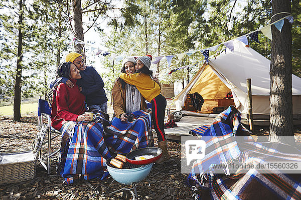 Glückliches  liebevolles lesbisches Paar und Kinder entspannen sich auf einem Campingplatz im Wald