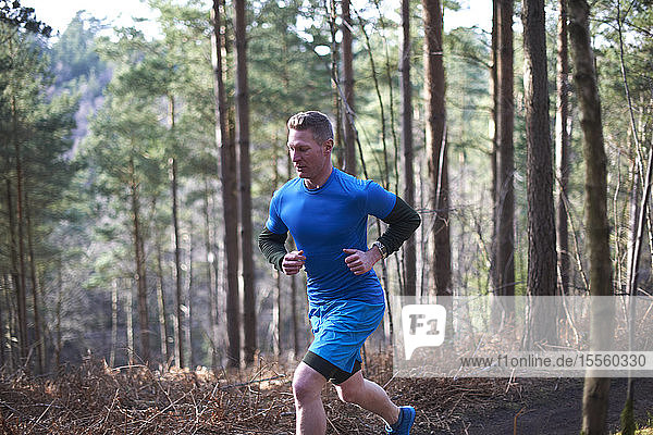Man running on trail in sunny autumn woods