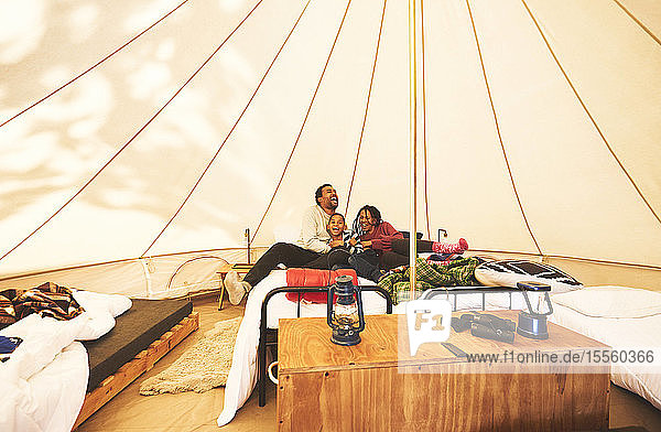 Glückliche  sorglose Familie  die sich auf einem Bett in einer Camping-Jurte entspannt
