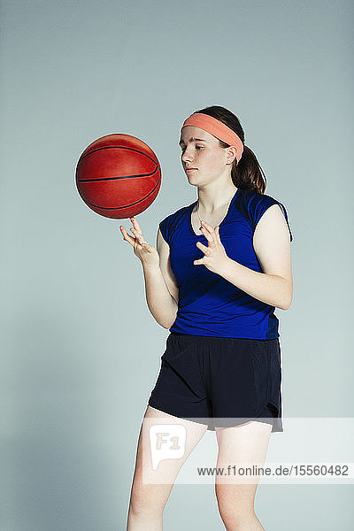 Basketballspielerin im Teenageralter  die den Basketball auf dem Finger dreht