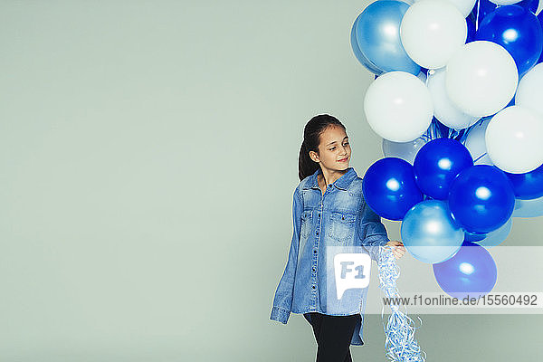 Lächelndes Mädchen mit blau-weißem Luftballonstrauß