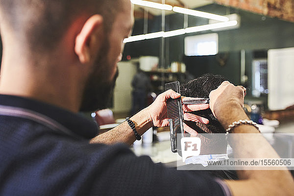 Männlicher Friseur schneidet einem Kunden die Haare im Friseursalon