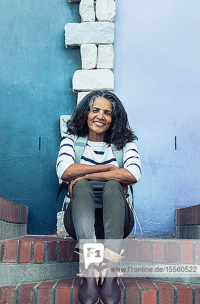 Porträt einer lächelnden  selbstbewussten Frau  die auf einer Backsteintreppe sitzt