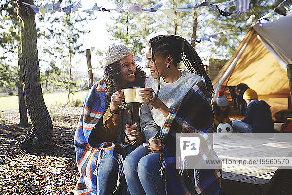 Glückliches lesbisches Paar  das sich auf einem sonnigen Campingplatz entspannt und Kaffee trinkt