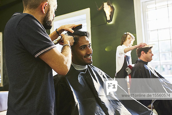 Smiling man receiving haircut at barbershop