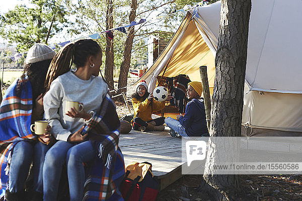 Lesbisches Paar beobachtet Kinder  die mit einem Fußball vor einer Camping-Jurte spielen