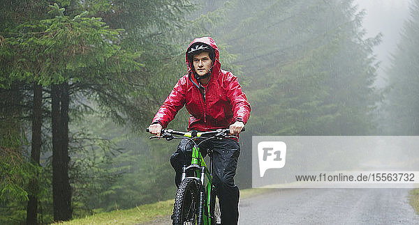 Mann beim Mountainbiken im Regen