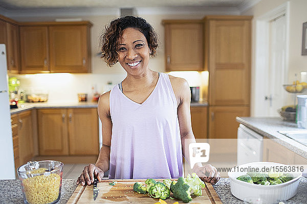 Porträt lächelnde  selbstbewusste Frau beim Kochen in der Küche