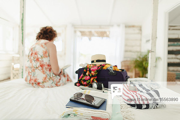 Woman unpacking suitcase in beach house bedroom