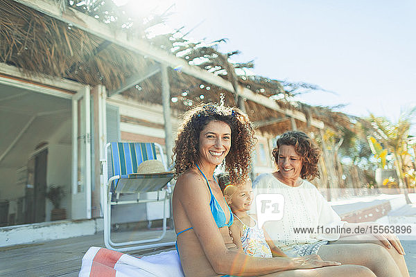 Portrait happy multi-generation women relaxing outside sunny beach hut