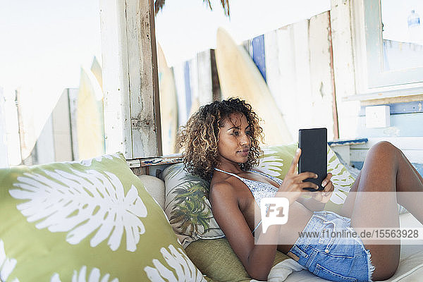 Junge Frau benutzt digitales Tablet auf einer Strandterrasse