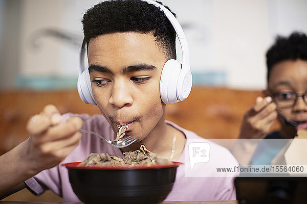 Teenage boy with headphones eating