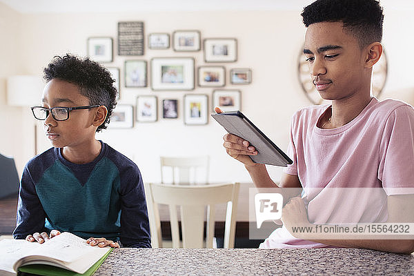 Brüder  die in der Küche lesen und ein digitales Tablet benutzen