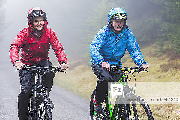 Vater und Sohn beim Mountainbiken im Regen