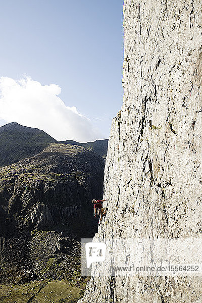 Male rock climber scaling large rock face