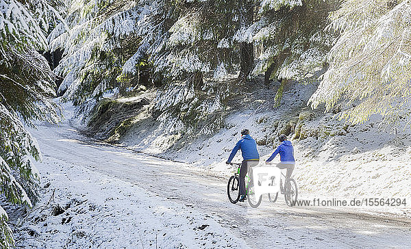 Pärchen beim Mountainbiking im verschneiten Wald