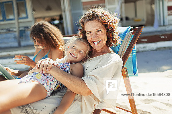 Portrait happy grandmother and granddaughter relaxing on sunny beach