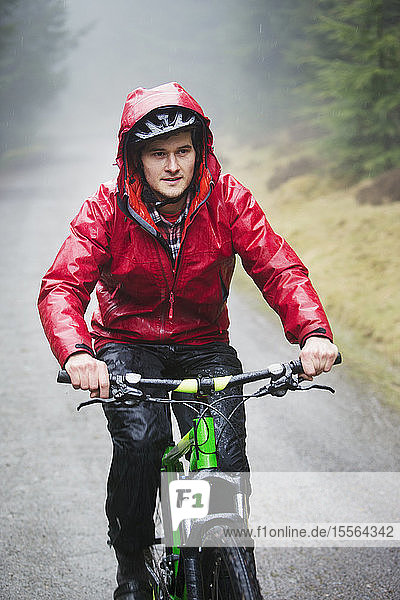 Mann beim Mountainbiken im Regen
