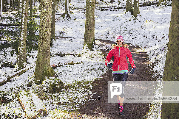 Frau joggt im verschneiten Wald