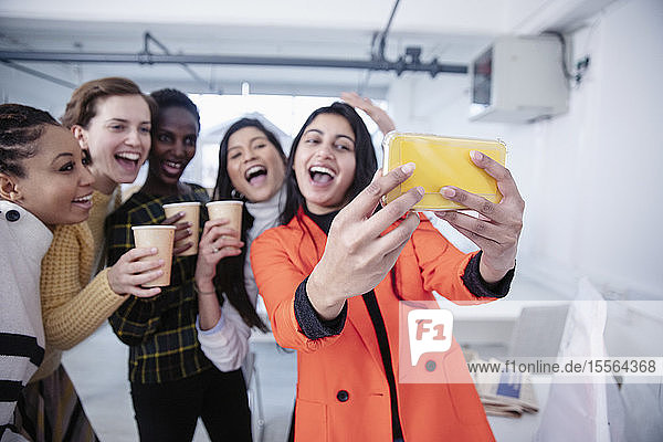 Glückliche Geschäftsfrauen beim Feiern und Selfie machen im Büro