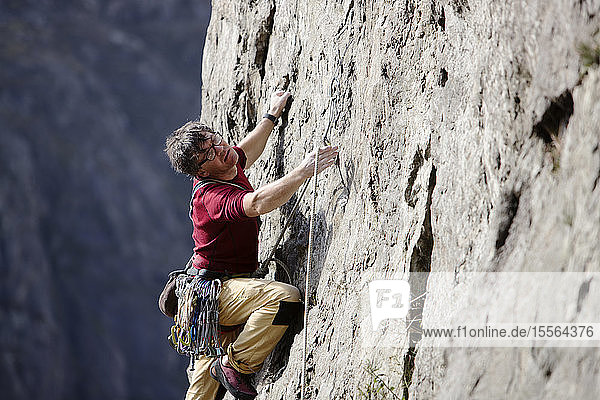 Männlicher Kletterer beim Erklimmen einer Felswand