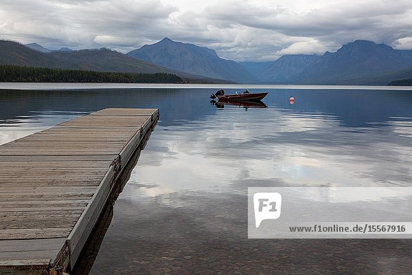 A boat rests at anchor in the evening calm waters of Lake McDonald in Glacier National Park in Montana.