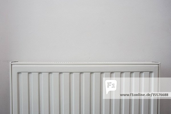 A White heating radiator on the white wall  modern design close-up.