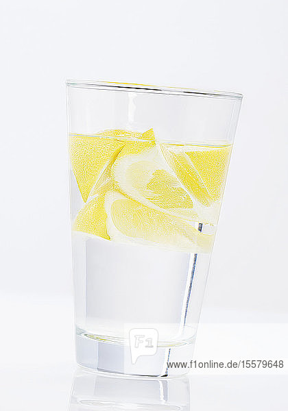 Wasserglas mit Zitronenscheiben auf weißem Hintergrund