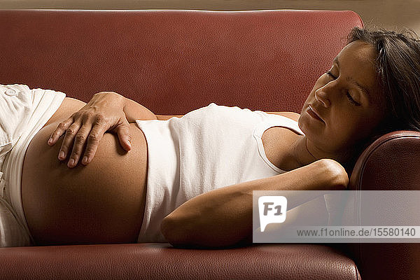 Schwangere Frau auf dem Sofa liegend  Augen geschlossen