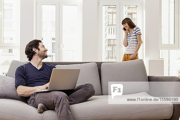 Couple using laptop and cell phone at home