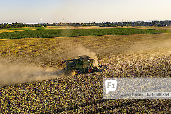Luftaufnahme eines Mähdreschers auf einem landwirtschaftlichen Feld gegen klaren Himmel bei Sonnenuntergang