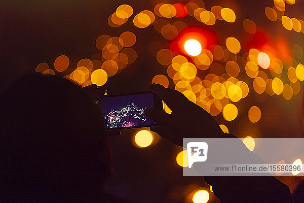 Silhouette einer Frau  die auf dem Christams-Markt mit einem Smartphone fotografiert