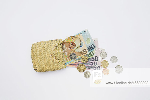 Notes and coins in flax on white background