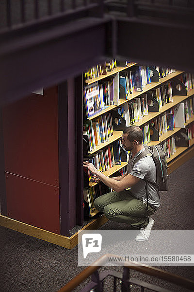Student in einer Bibliothek am Bücherregal