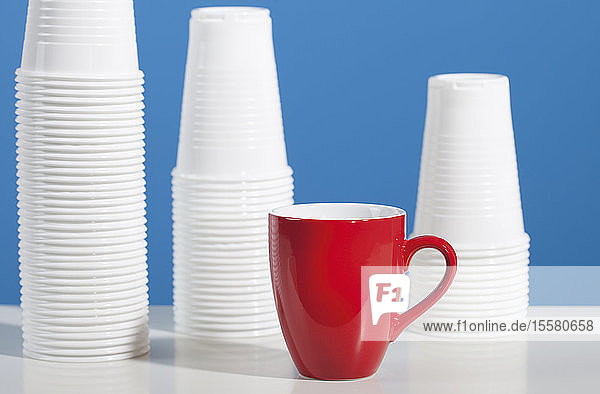 Rote Kaffeetasse vor Plastikbechern auf dem Tisch
